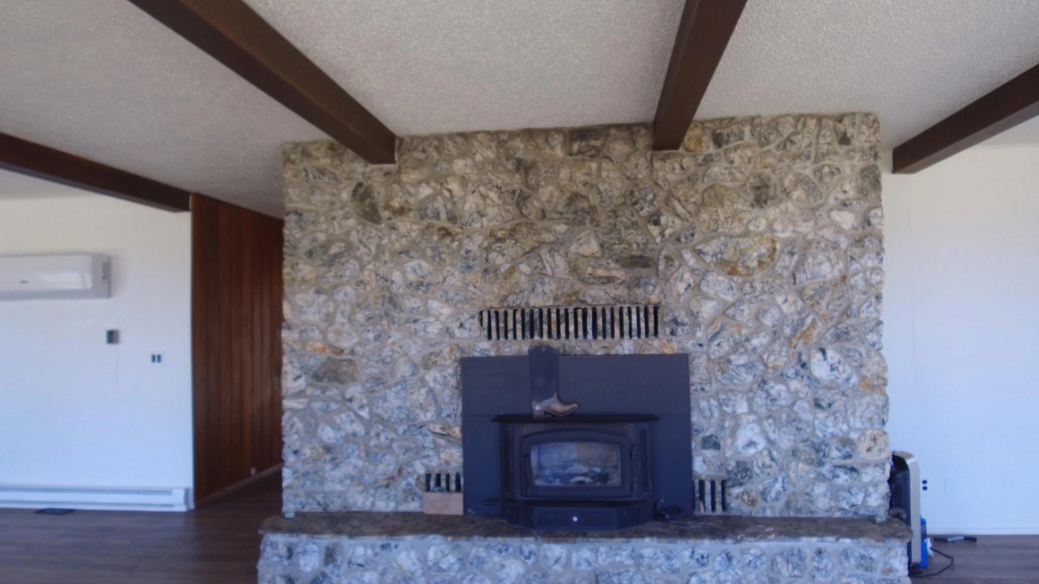 Stone fireplace and exposed ceiling beams inside the Andy Hill Road home